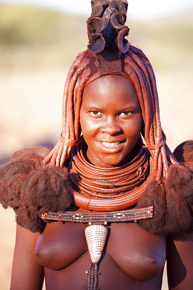 Young Himba woman wearing traditional dress and jewellery and with her skin covered in Otjize, a mixture of butterfat and ochre, Kunene Region, formerly Kaokoland, Namibia, Africa