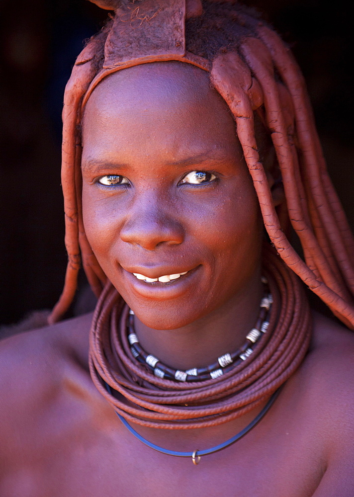 Young Himba woman wearing traditional dress and jewellery and with her skin covered in Otjize, a mixture of butterfat and ochre, Kunene Region, formerly Kaokoland, Namibia, Africa