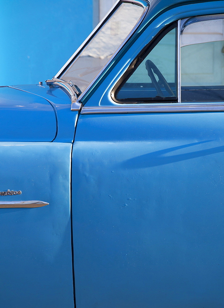 Detail of vintage blue American car against painted blue wall, Cienfuegos, Cuba, West Indies, Central America 