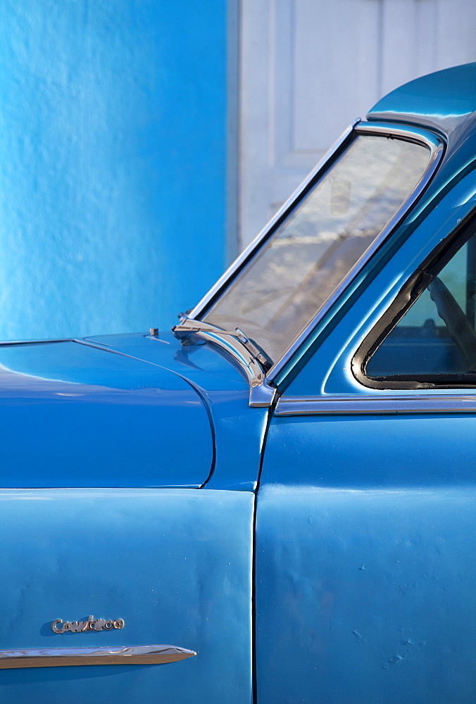 Detail of vintage blue American car against painted blue wall, Cienfuegos, Cuba, West Indies, Central America 