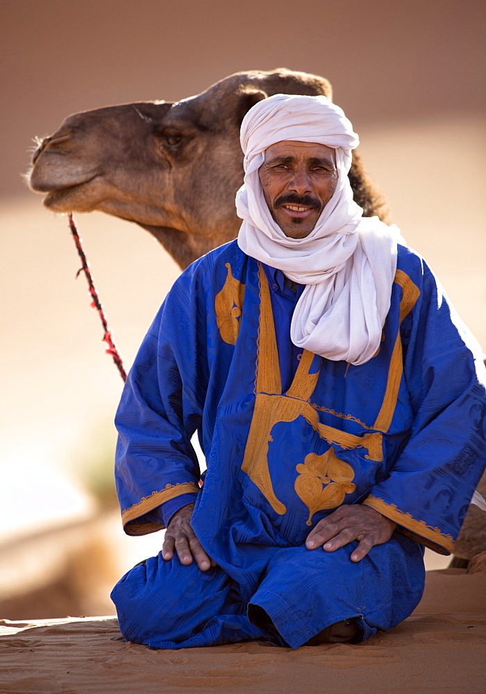 Berber man with camel, resting in the Erg Chebbi Sand sea, part of the Sahara Desert near Merzouga, Morocco, North Africa, Africa