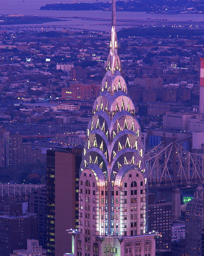 The top of the Chrysler Building illuminated in the evening with a bridge and the city of New York in the background, United States of America, North America