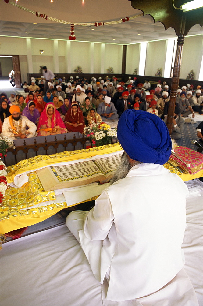 Sikh priest and holy book at Sikh wedding, London, England, United Kingdom, Europe