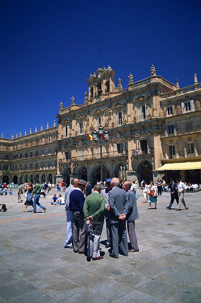 A group of men talking in front of the town hall in the Plaza Mayor, in Salamanca, Castilla y Leon, Spain, Europe