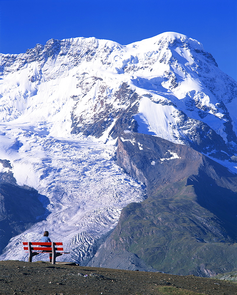 Hiker on bench, The Breithorn and Breithorn Glacier, Rotenboden, Zermatt, Valais, Switzerland, Europe