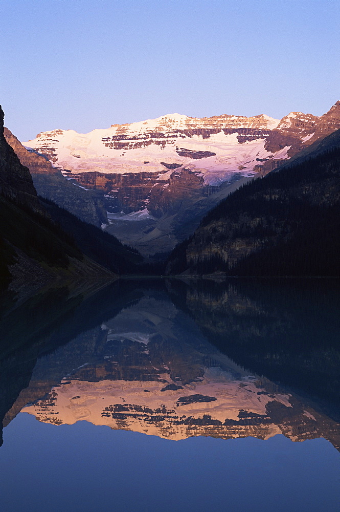 View to Mount Victoria across the still waters of Lake Louise, at sunrise in summer, Banff National Park, UNESCO World Heritage Site, Alberta, Canada, North America