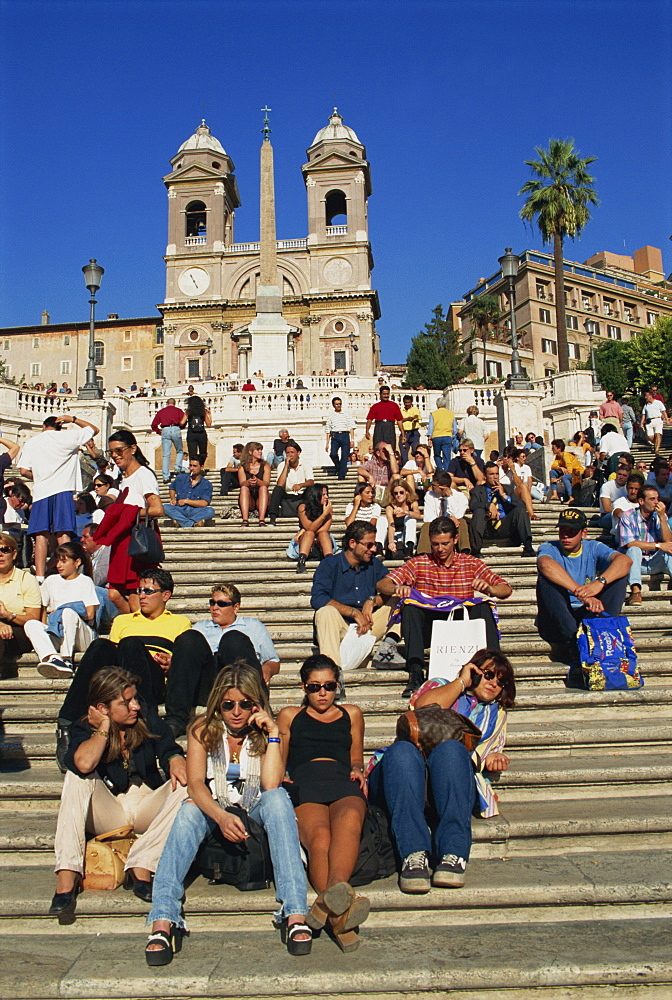 Groups of tourists sitting on the Spanish Steps with the Trinite dei Monti behind, in Rome, Lazio, Italy, Europe