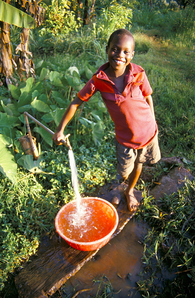 Boy at water tap, Chuka village, Mount Kenya, Kenya, East Africa, Africa