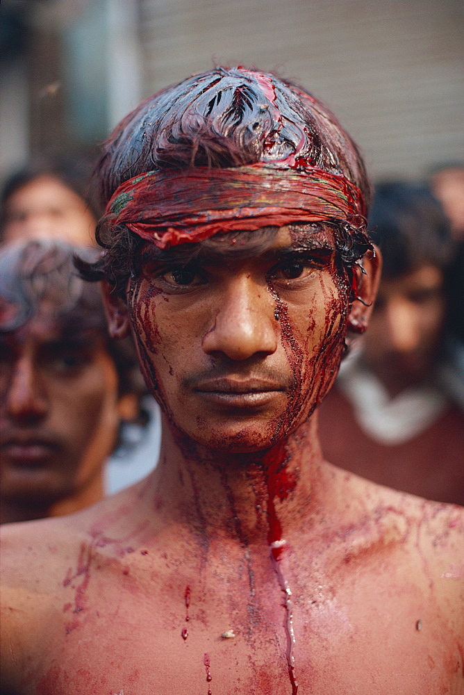 Portrait of a man with head wounds from beating himself with a knife, the bleeding stopped by a headband, during Moharran in Lahore, Punjab, Pakistan, Asia