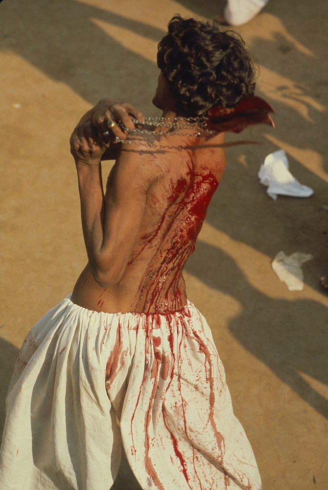 A man beating himself with a knife bundle, encouraged with songs of mourning for Husayns death, during Moharran in Lahore, Punjab, Pakistan, Asia