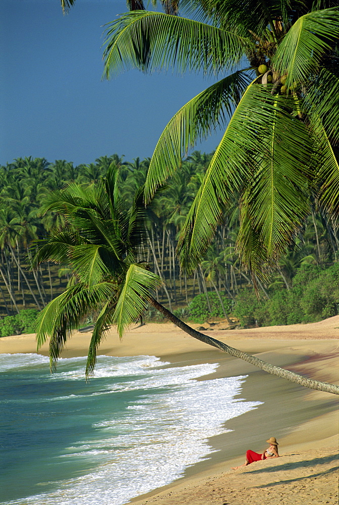 Woman relaxing on empty beach, Tangalla, Sri Lanka, Asia