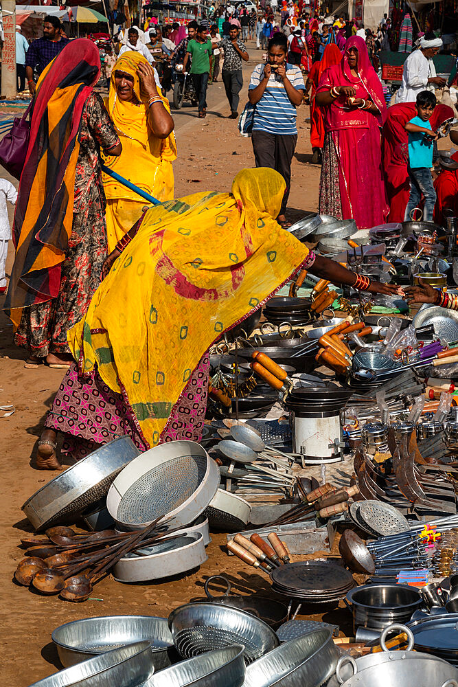 Rajasthani women in brightly coloured traditional clothing shopping for kitchen utensils, Pushkar Fair, Pushkar, Rajasthan, India, Asia