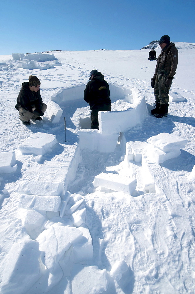 Inuit cutting snow blocks using a saw and a knife to make an igloo, Nunavut, Canada, North America