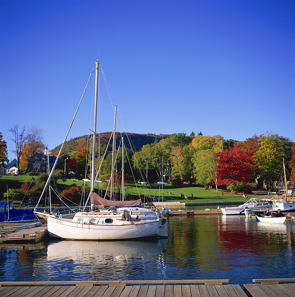 Boats on the waterfront at Camden harbour with fall colours and Mount Battie in the background, Maine, New England, United States of America, North America