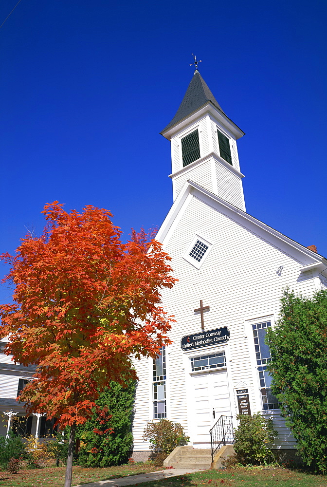 A small maple tree in fall colours before the Center Conway United Methodist Church, New Hampshire, New England, United States of America, North America