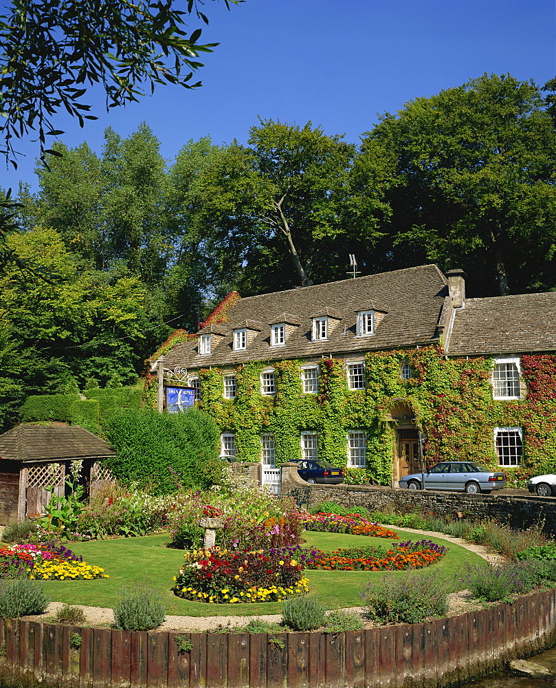 The Swan Hotel and garden full of summer flowers at Bibury, in the Cotswolds, Gloucestershire, England, United Kingdom, Europe