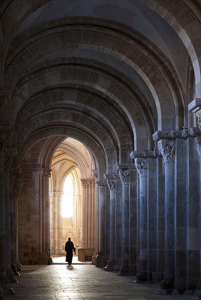 Interior north nave aisle with priest walking away, Vezelay Abbey, UNESCO World Heritage Site, Vezelay, Burgundy, France, Europe