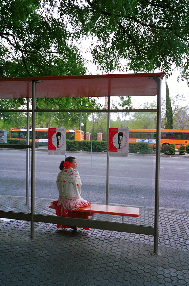 Seville - Spain - The Feria de Abril - Seville Fair - A girl in traditional costume waiting at a bus stop 