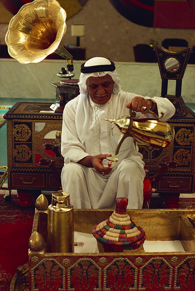 Elderly man in traditional dress pouring drink, Bahrain, Middle East