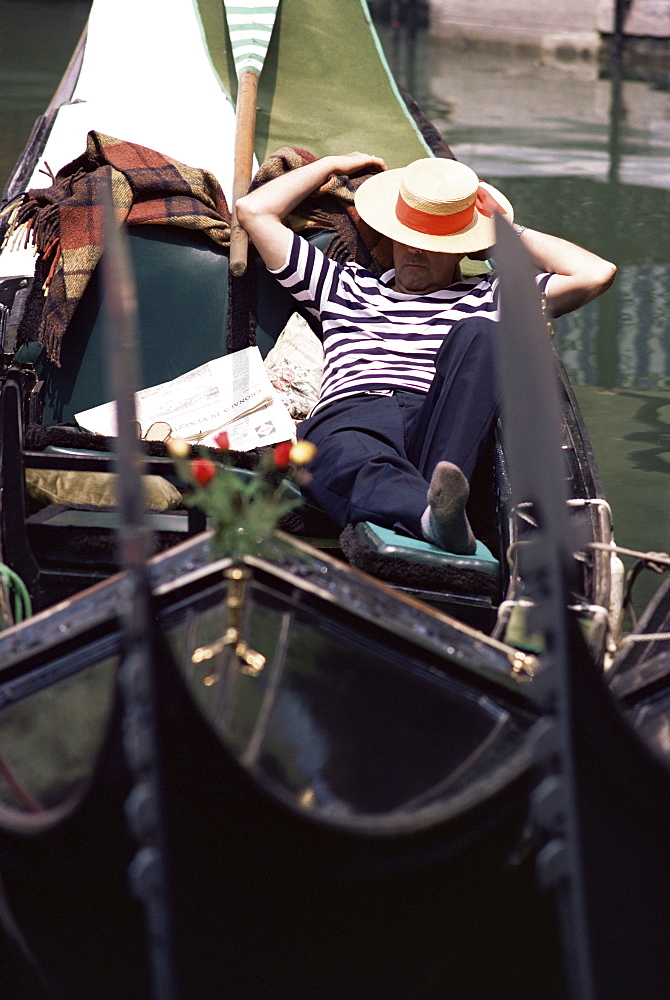 Gondolier relaxing in gondola, Venice, Veneto, Italy, Europe