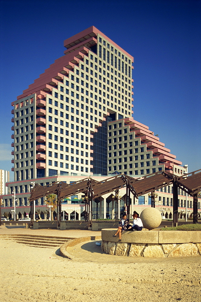 Two women talking on the beach, with the Opera Tower in the background, in Tel Aviv, Israel, Middle East