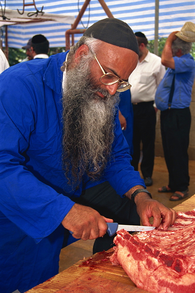 Orthodox Jewish butcher with glasses and long beard, cuts meat at Meron, Israel, Middle East