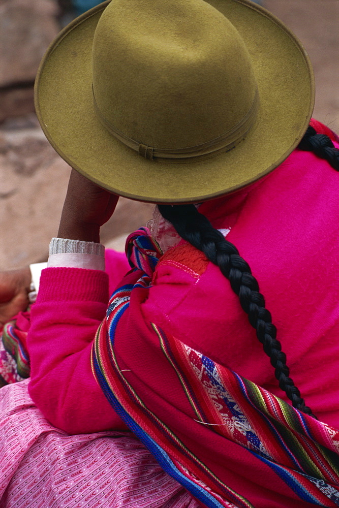 The back of an Indian woman wearing a felt hat and plaited hair in the market at Pisac in the Cuzco area, Peru, South America