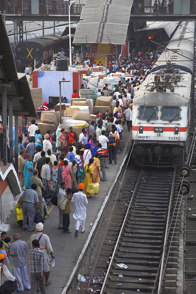 Train ariving at crowded platform in New Delhi train station, Delhi, India, Asia