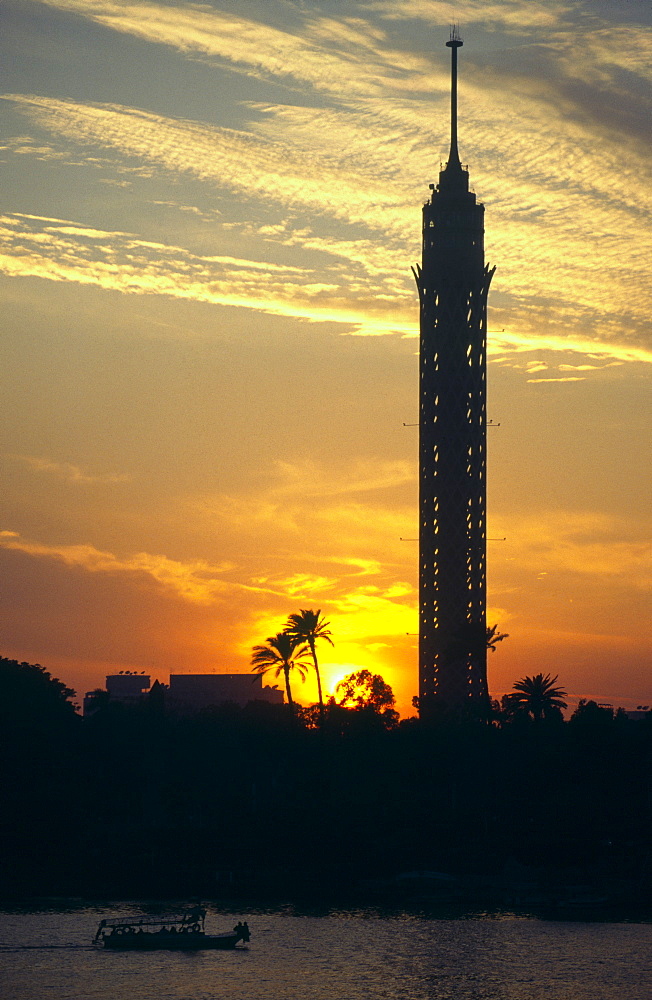 View at sunset of the Tower of Cairo and palm trees with small boat on River Nile in foreground, Cairo, Egypt, North Africa, Africa