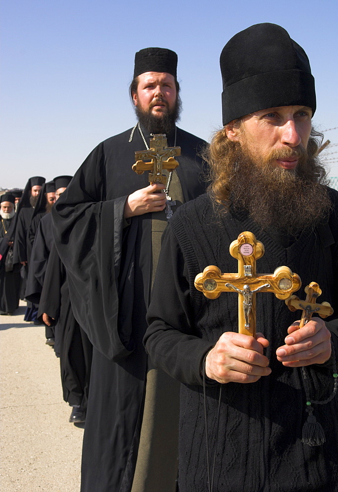 Priests in black holding olive wood crosses in procession to the River Jordan during Christian Orthodox ceremony at Epiphany, Qasr el Yahud, Israel, Middle East