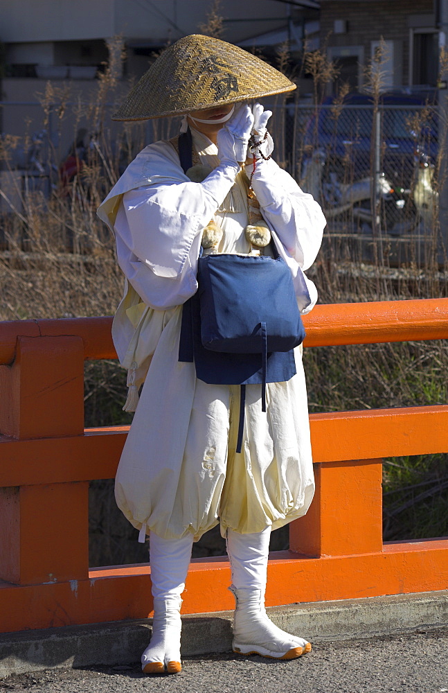 Pilgrim wearing traditional hat and white clothes standing on a bridge and praying, near Fushimi Inari Taisha shrine, Kyoto, Kansai, Honshu, Japan, Asia