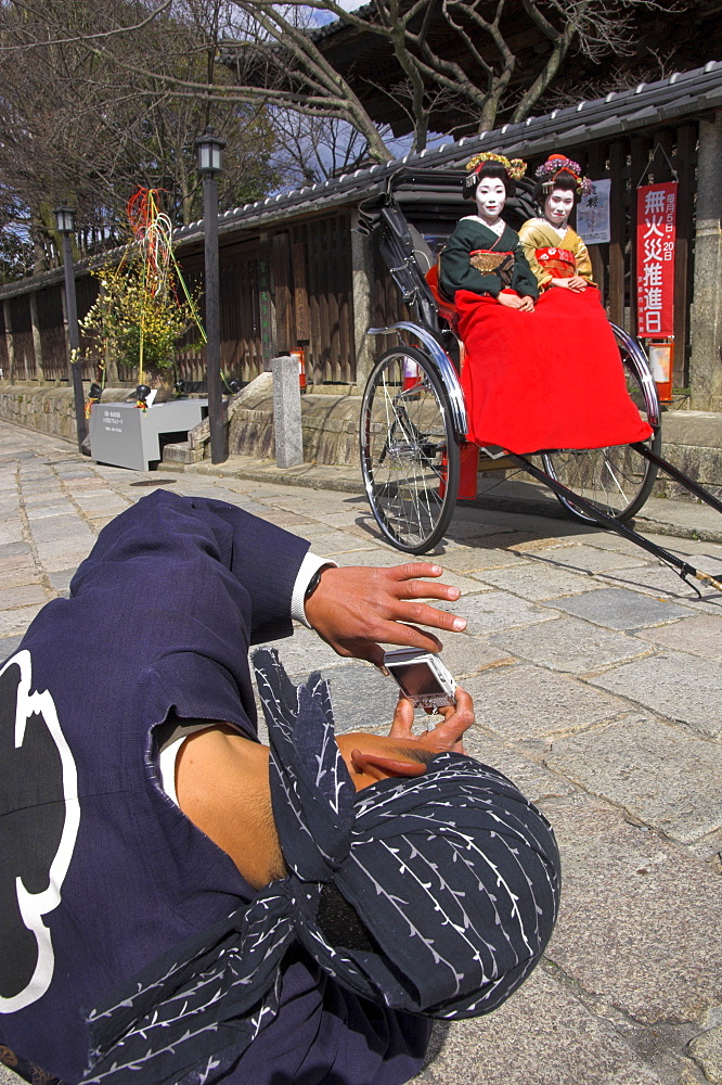 Driver taking picture of two geishas in traditional dress posing on a rickshaw, Higashiyama neighbourhood, Kyoto, Kansai, Honshu, Japan, Asia