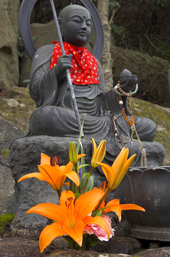 Traditional bronze figure of Buddha with red scarf and fresh flowers, Daisho In temple, Miyajima, Honshu, Japan, Asia