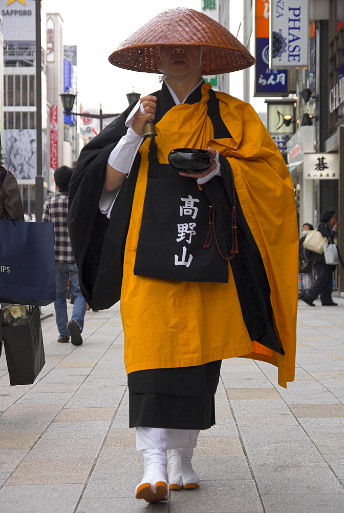 Shinto monk in traditional dress walking on pavement collecting donations, Ginza, Tokyo, Honshu, Japan, Asia