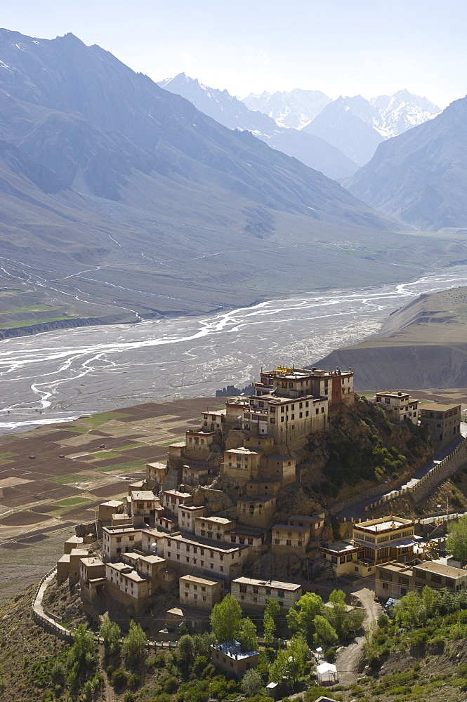 Backlit view of Kee Gompa monastery complex from above, with Spiti valley and snowy mountains beyond, Spiti, Himachal Pradesh, India, Asia