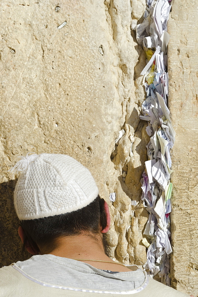 Orthodox Jew praying at Western Wall, with paper notes in crack, Old City, Jerusalem, Israel, Middle East