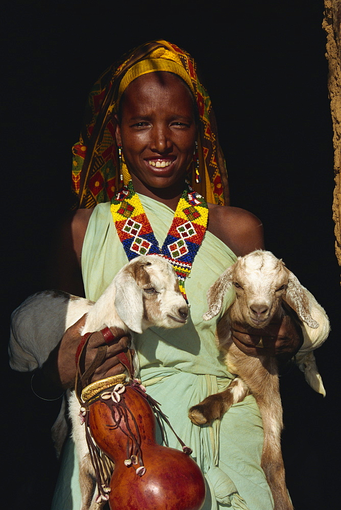 Woman holding twin kid goats and gourd, and wearing beads, Harar, Ethiopia, Africa