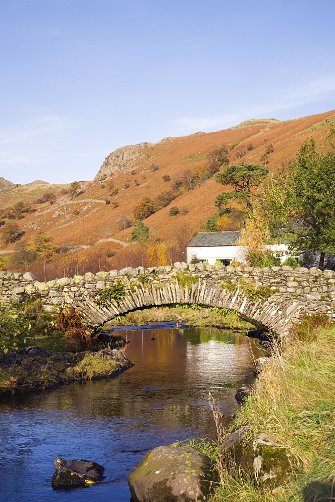 Old stone packhorse bridge over Watendlath Beck in picturesque village in autumn, Watendlath, Lake District National Park, Cumbria, England, United Kingdom, Europe