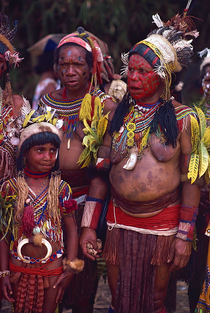 Portrait of two women and a girl with facial decoration and wearing jewellery and head-dresses, in Papua New Guinea, Pacific Islands, Pacific