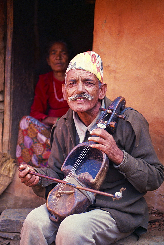 Portrait of a man of Gaines, caste of musicians, playing a stringed instrument and looking at the camera, in Pokhara, Nepal, Asia