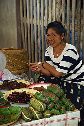 Portrait of a young Laotian woman smiling and looking at the camera, selling food in a street market in Luang Prabang in Laos, Indochina, Southeast Asia, Asia