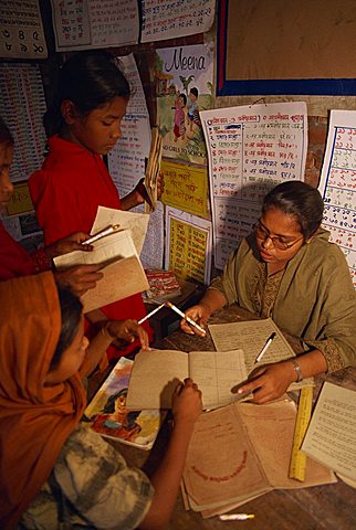 A Bangladeshi woman teacher marks students books in a school in the slums of Dhaka (Dacca), Bangladesh, Asia