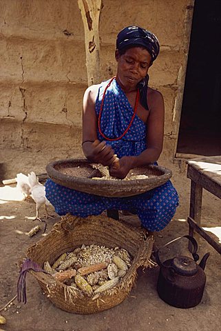 Portrait of woman in traditional clothing, sitting outside, stripping corn (maize), Somalia, Africa