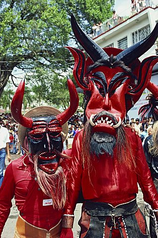 Portrait of two people with devil masks, wearing red, looking at the camera, during Easter celebrations at Ciudad Santos in Mexico, North America