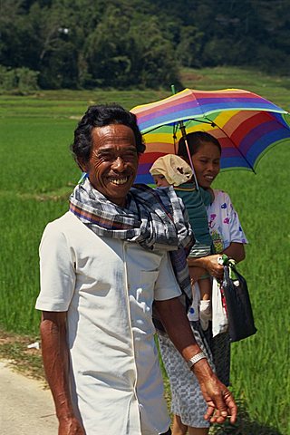 Portrait of a family, mother, father and baby, walking through a rice field, the man smiling and looking at the camera, Toraja area, Sulawesi, Indonesia, Southeast Asia, Asia