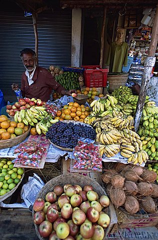 Elderly man at his fruit stall in Munnar a small town in the tea country high in the Western Ghats, Kerala, India, Asia