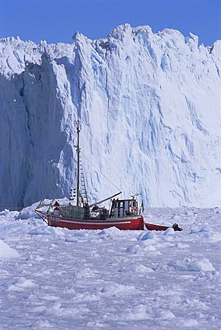 Red wooden boat crossing the ice in front of the Eqi Glacier, near Ilulissat, Greenland, Polar Regions