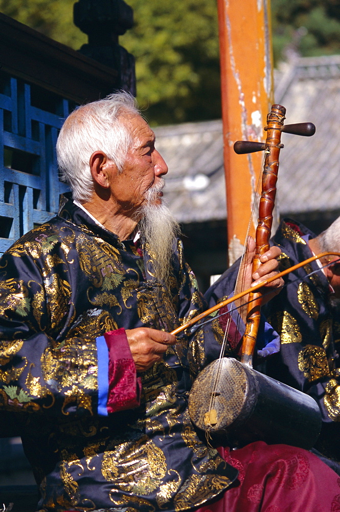 Portrait of an elderly musician from the Naxi orchestra practising by the Black Dragon Pool, Lijiang, Yunnan Province, China, Asia