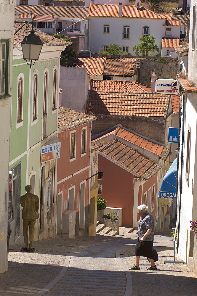 An elderly woman walks across the street in Monchique, Algarve, Portugal, Europe