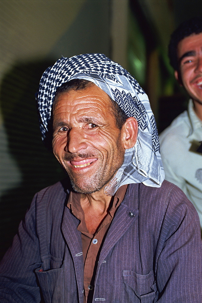 Head and shoulders portrait of a Kurdish man wearing a kaffiyeh, smiling and looking at the camera, in the Souk, Erbil, Kurdistan, Iraq, Middle East